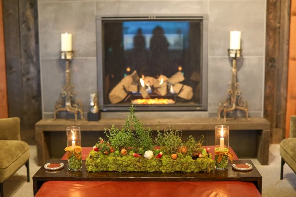 Elegant moss centerpiece and candles on a leather ottoman in front of a stone fireplace at Big Vista Ranch