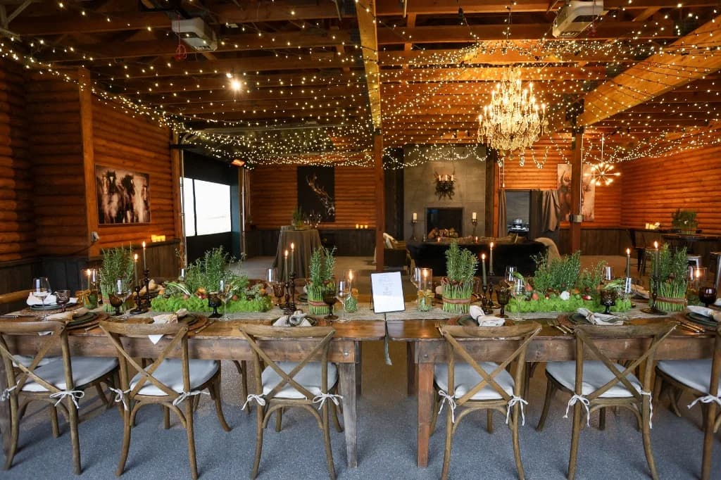 Long rustic dining table set for a corporate dinner under string lights and chandelier at Big Vista Ranch