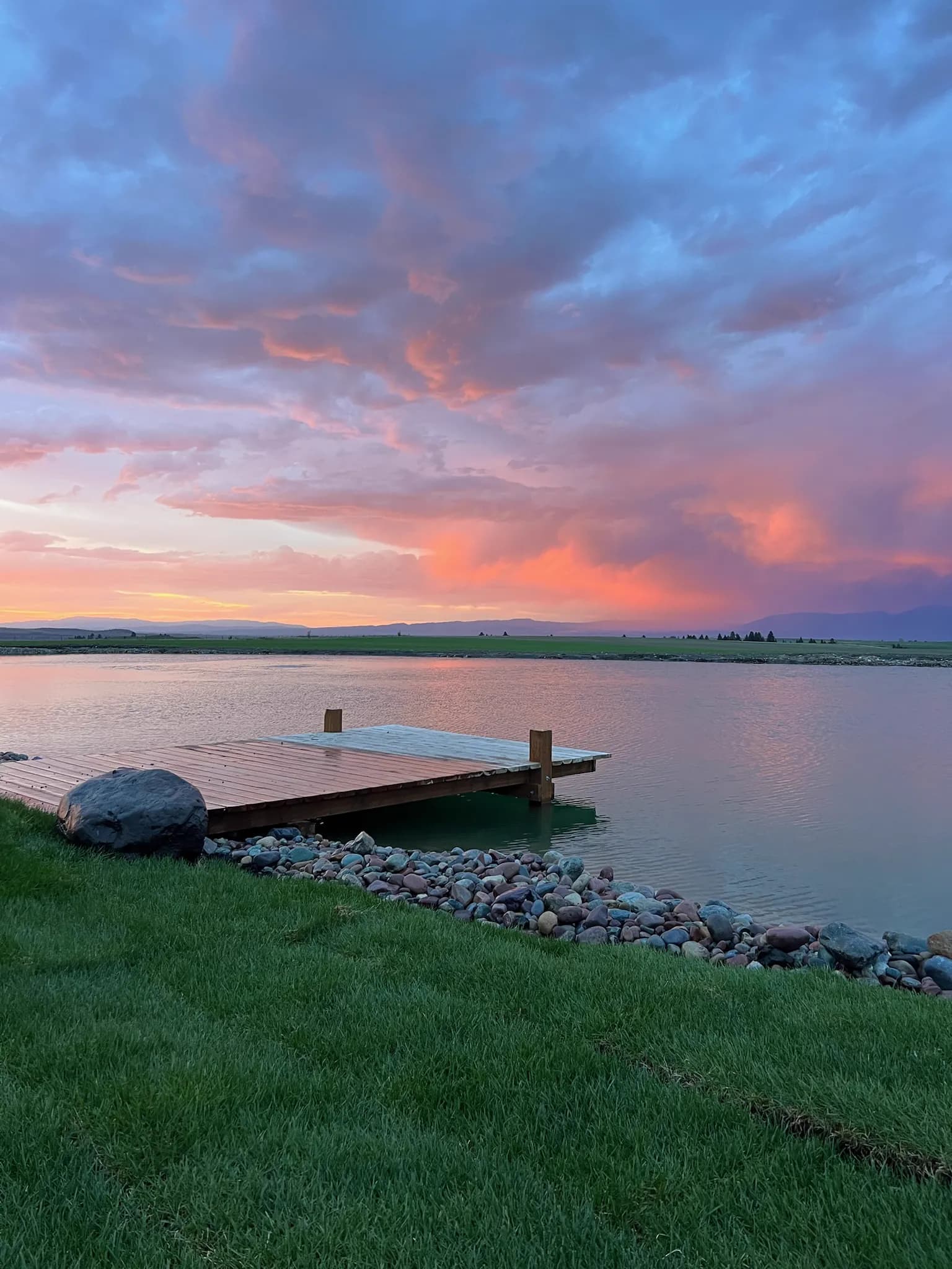 Small wooden dock leading out into the lake at sunset