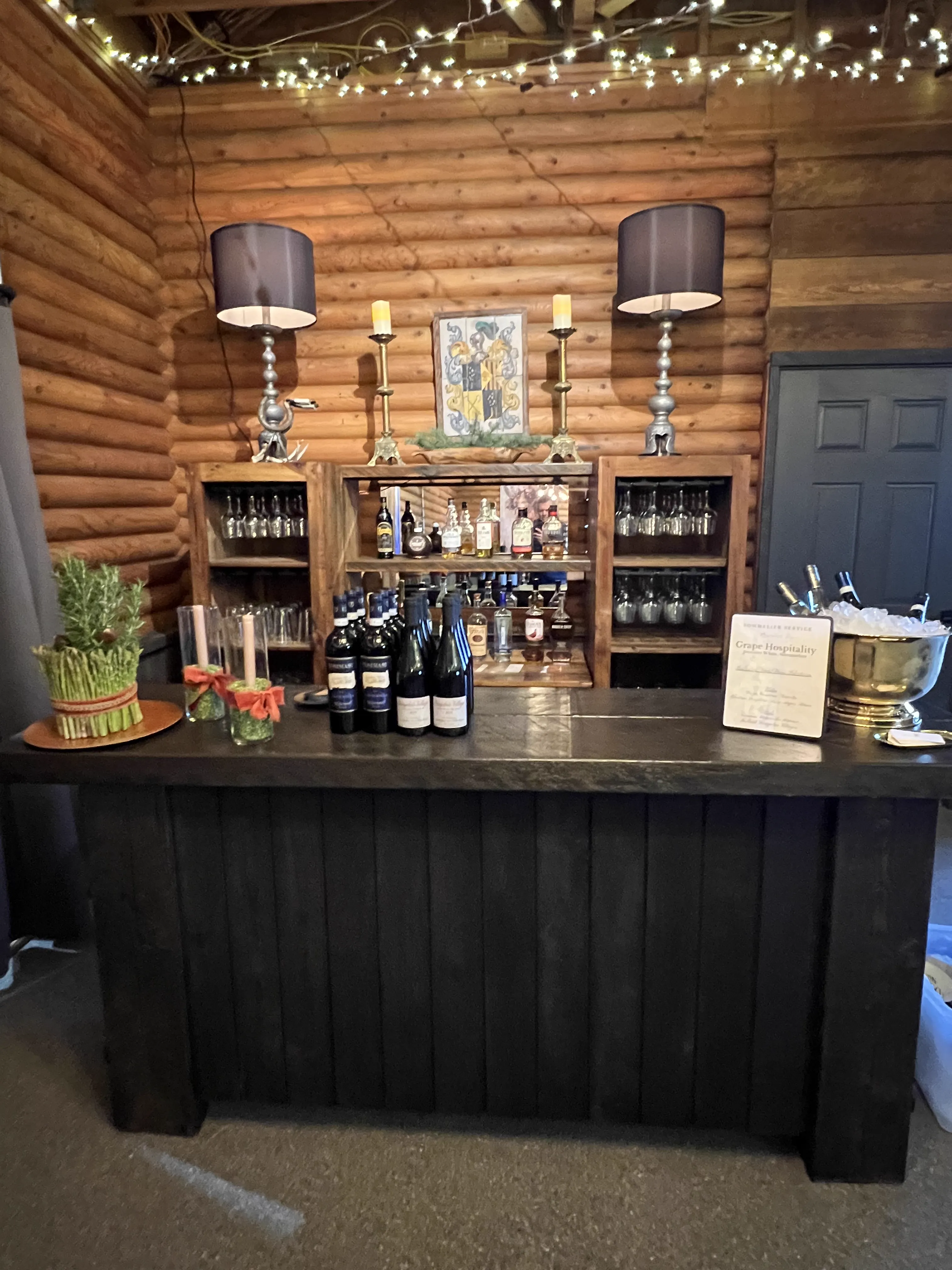 Rustic wooden bar setup inside a log cabin with wine bottles and glowing candles