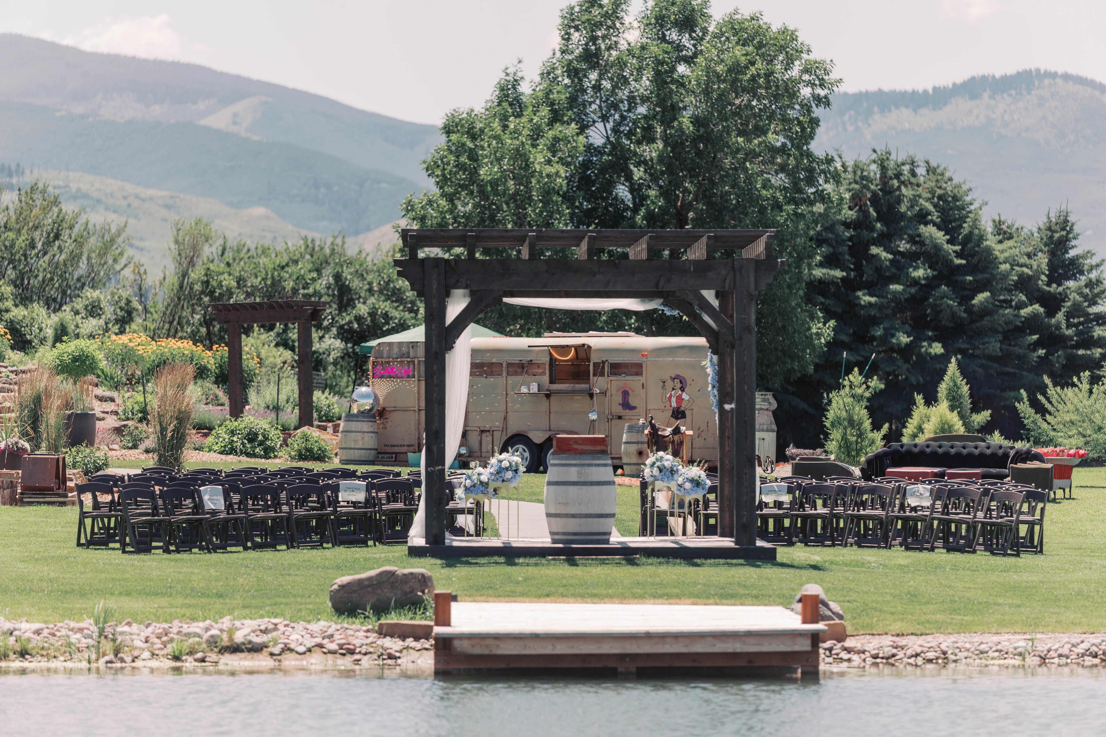 Wooden ceremony arch and rows of chairs on the lawn, viewed across the lake.
